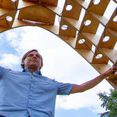 A man holding together a structure that has plant pots on it.