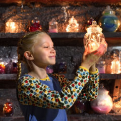 A girl holding a jar with fairy lights inside it.