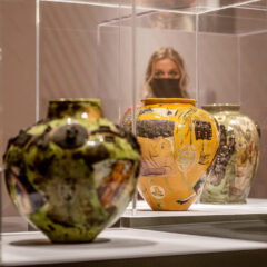 Three Grayson Perry ceramics in plinths. A visitor is in the background looking at the works.